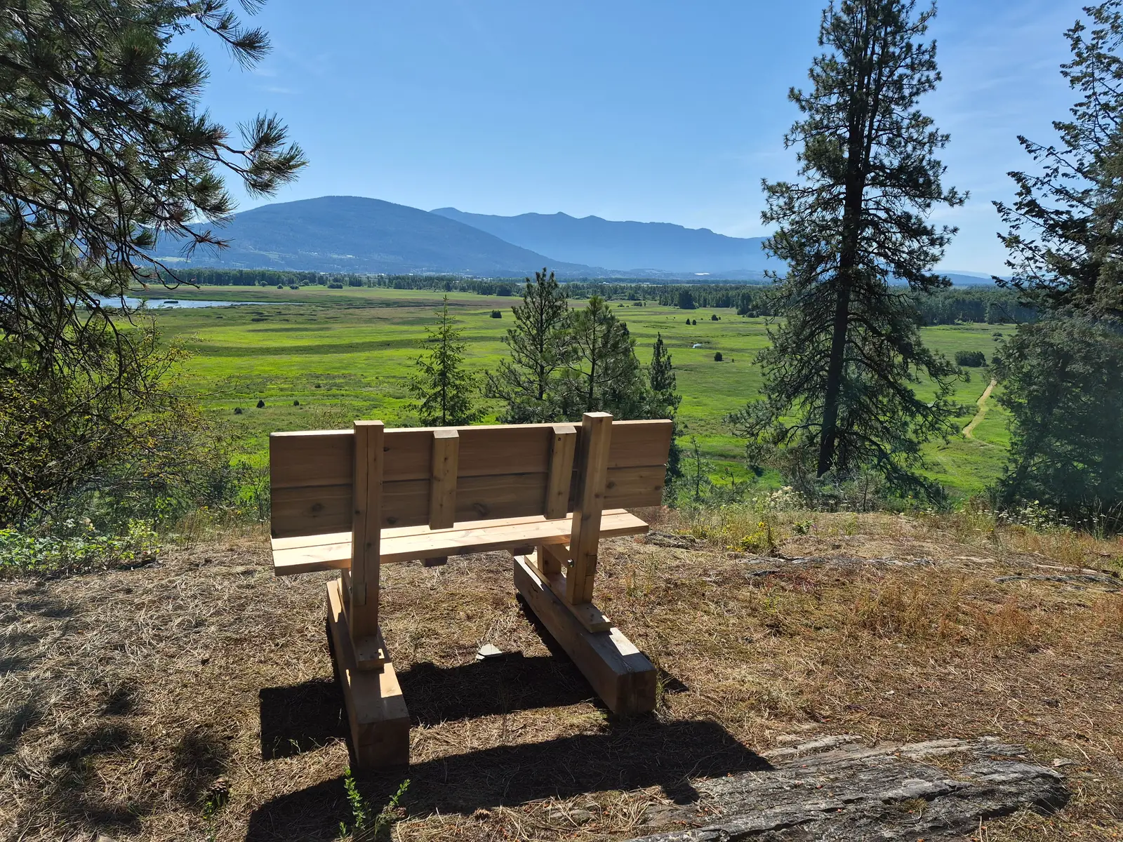 A bench at a trail viewpoint looking out over the Creston Valley